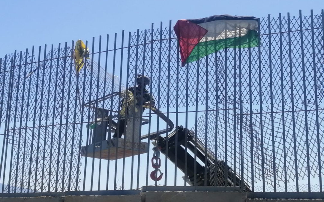 دورية اسرائيلية تعمل على نزع الأعلام التي رُفعت على السياج الحدودي